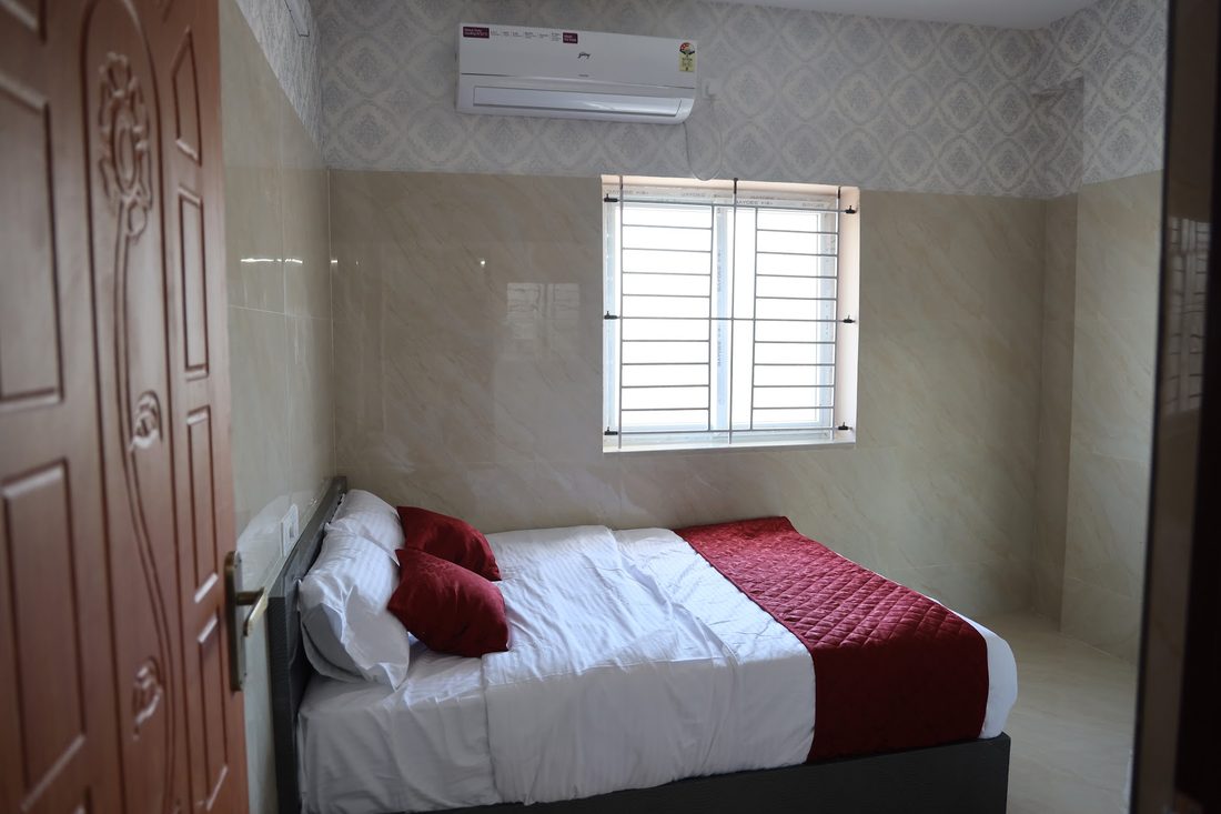 A bedroom with a carved teak door standing open beside the bed.