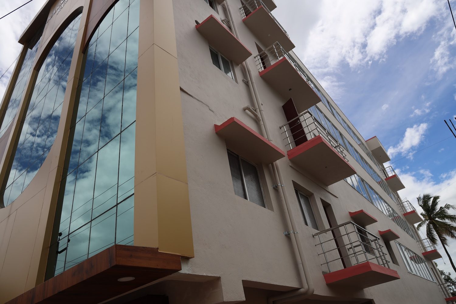 The glazed entrance tower seen from below, reflecting cloud, with the balconies running up the side of the building.
