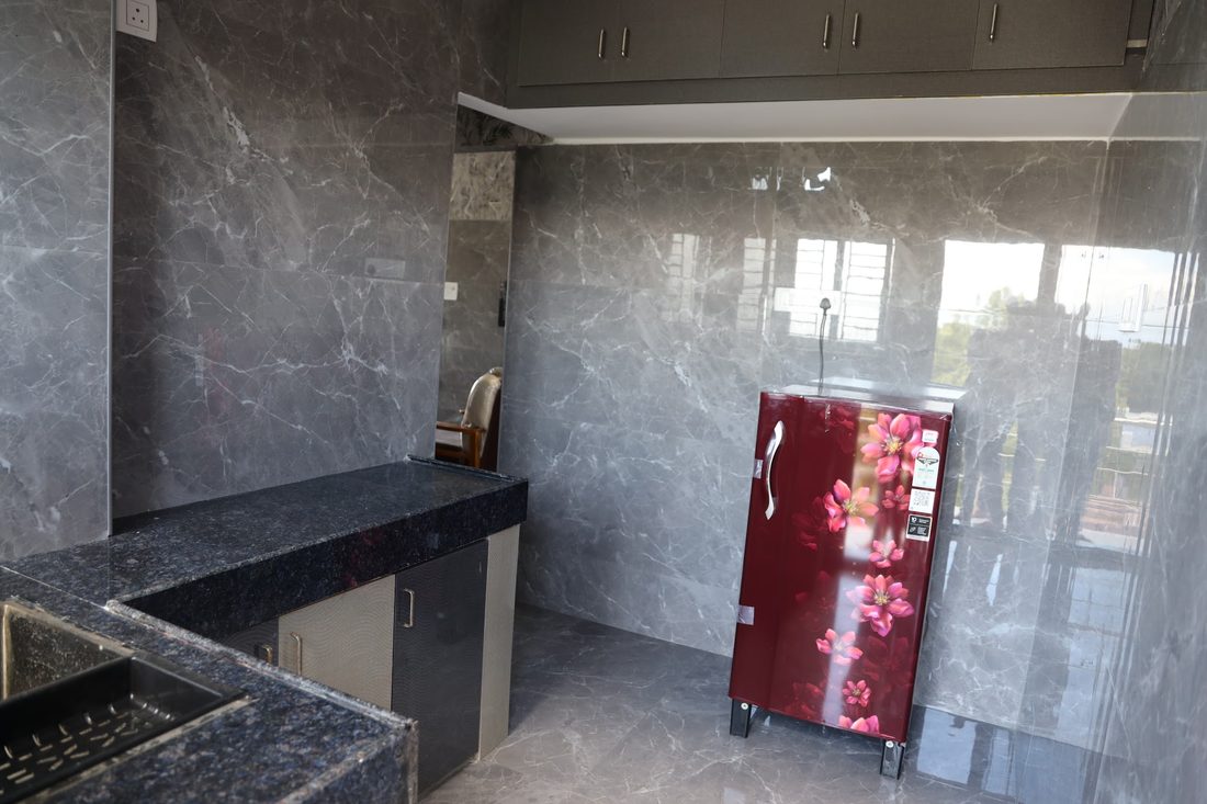 A kitchen with a granite counter along the wall and a refrigerator beside the window.