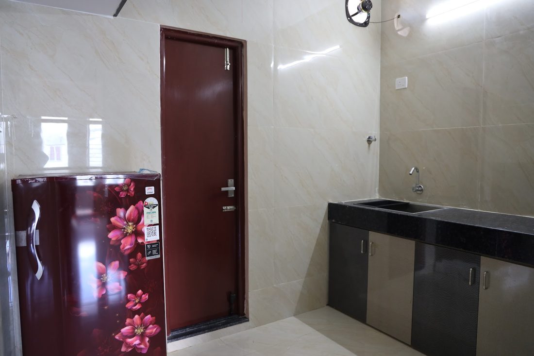 A compact kitchenette with a granite counter, sink and a refrigerator next to the entrance door.